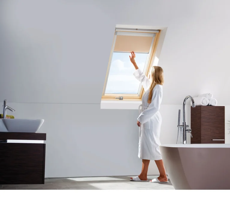 Meisje bij een enkel houten Keylite dakraam in een lichte kamer.