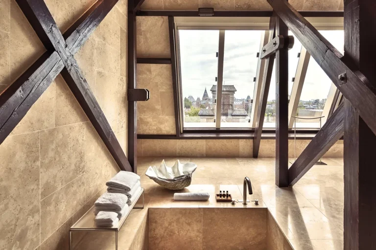 Licht hotelinterieur met glazen dakconstructie en houten afwerking.
