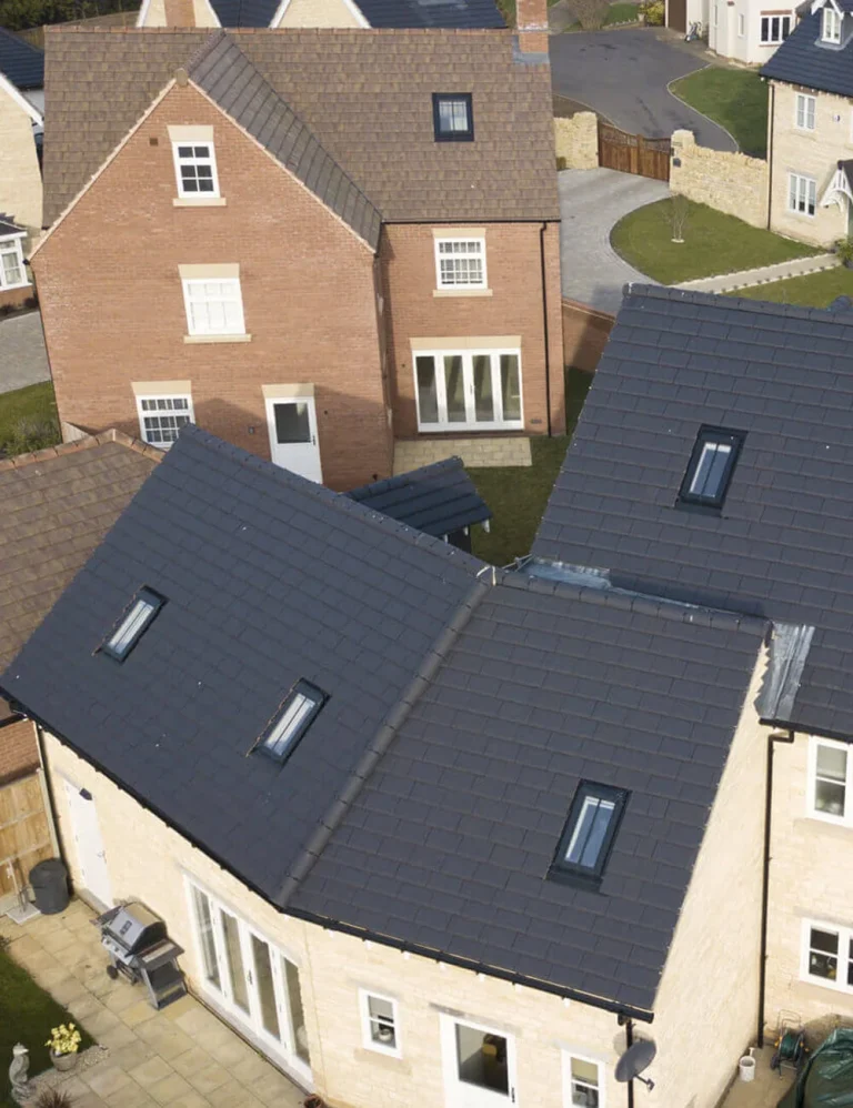 Luchtfoto van moderne woningen met donkere daken en meerdere dakramen.